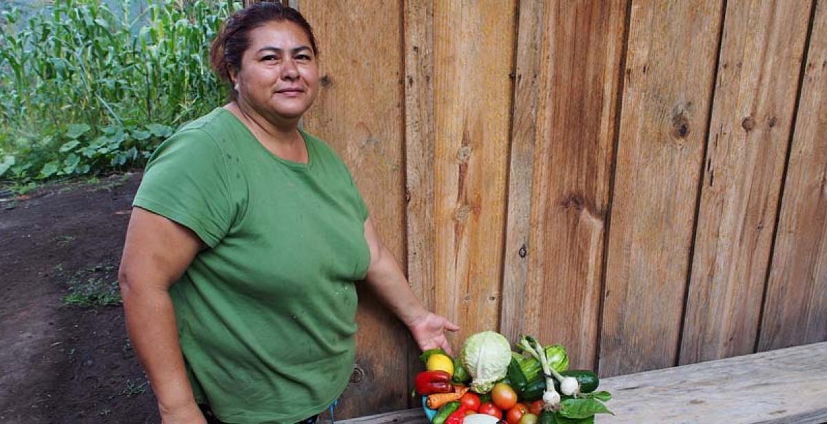 Gladys with her veg grown from seeds given by ASOMUPRO