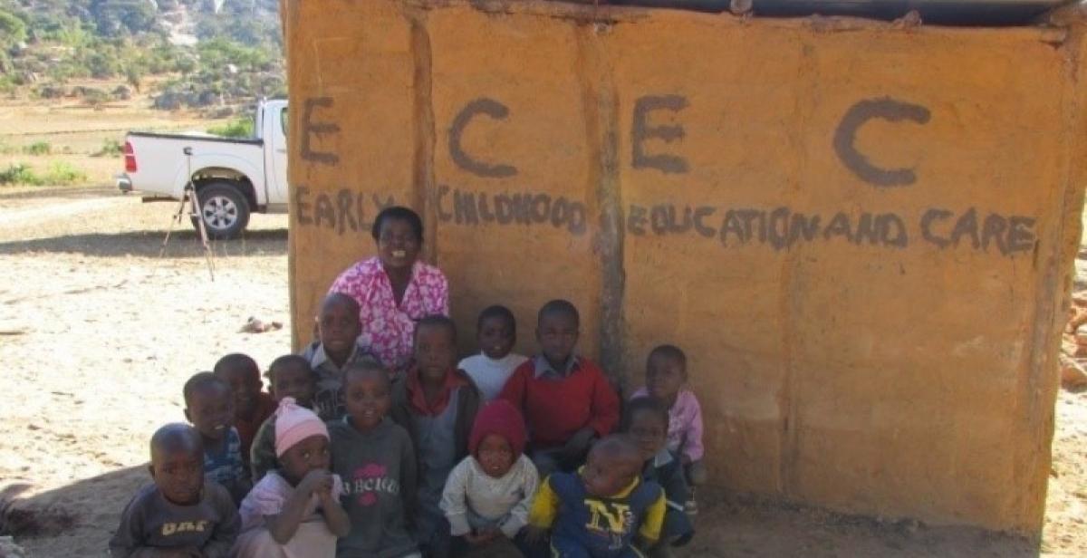 A Zimbabwean teacher sits in front of her school with he4r pupils