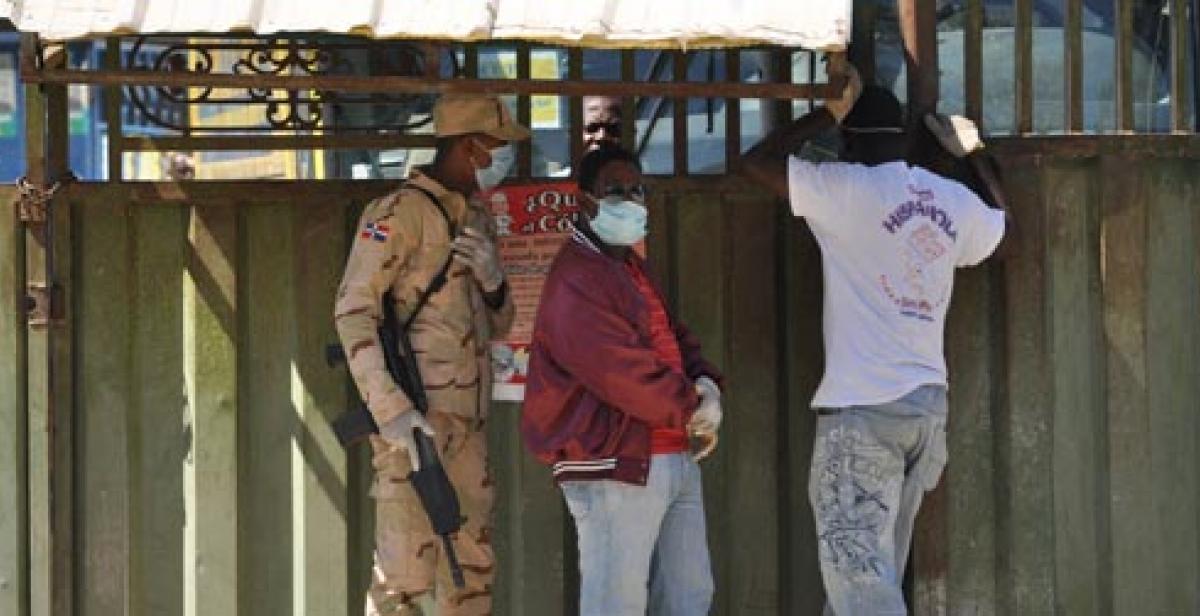 Three people wait at the border in Jimaní