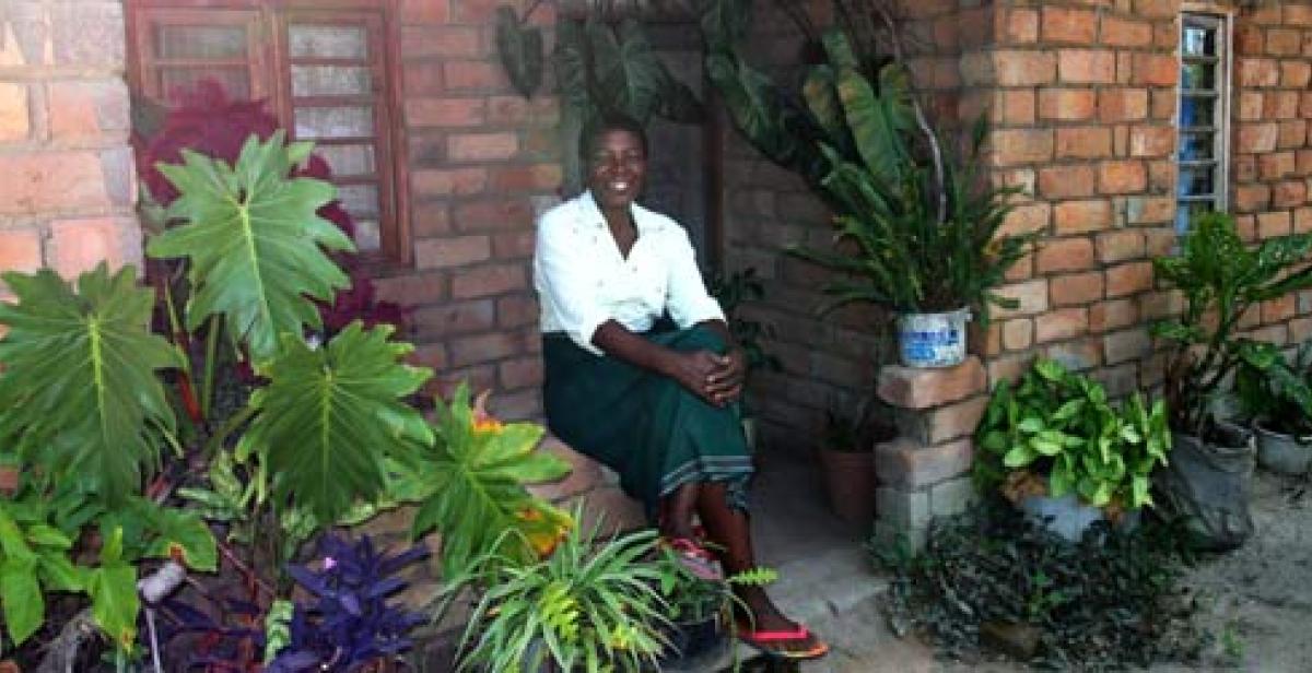 Portrait of Nifa Chumachiyenda, a farmer in Malawi, outside her house