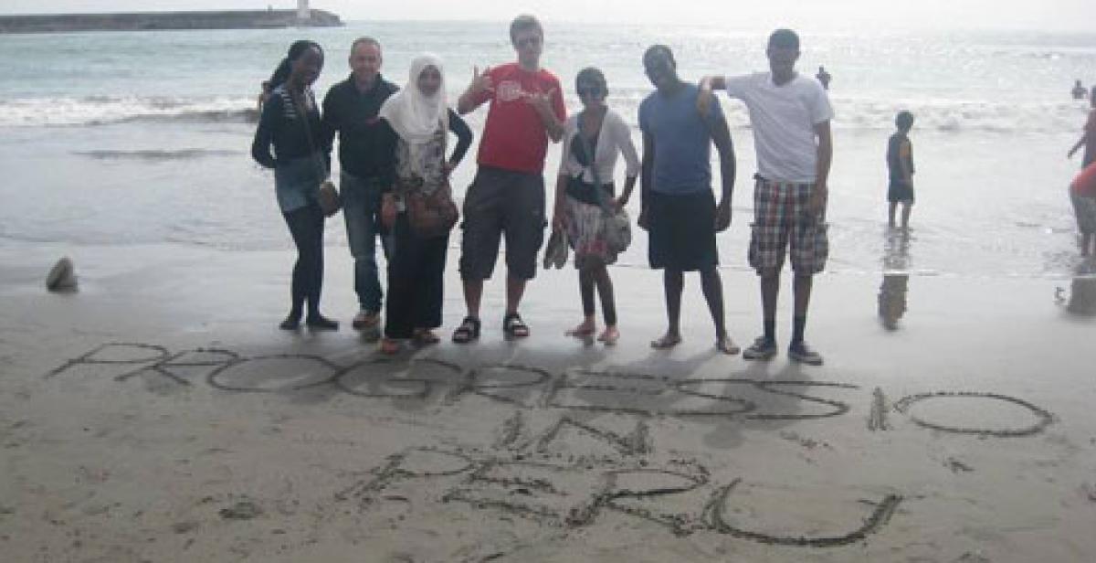 Empower volunteers on the beach in Lima, writing in the sand &quot;Progressio Peru&quot;