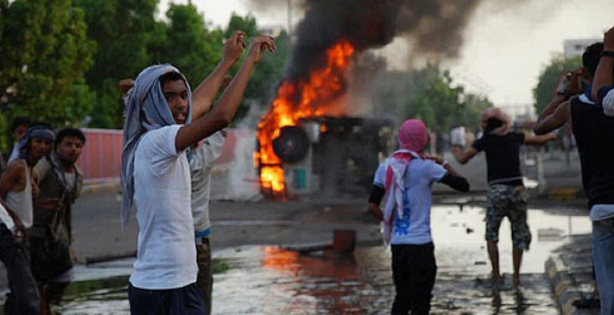 People protest in front of burning vehicle in Aden Yemen