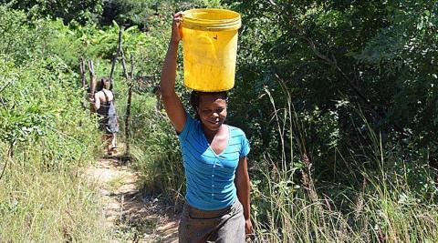 Takudzwa (a national volunteer) bringing water up from the Odzi River to water the garden