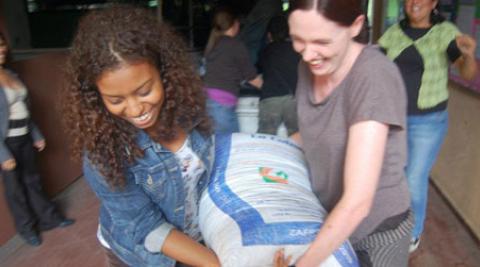 Two Progressio volunteers carry a sack of emergency supplies